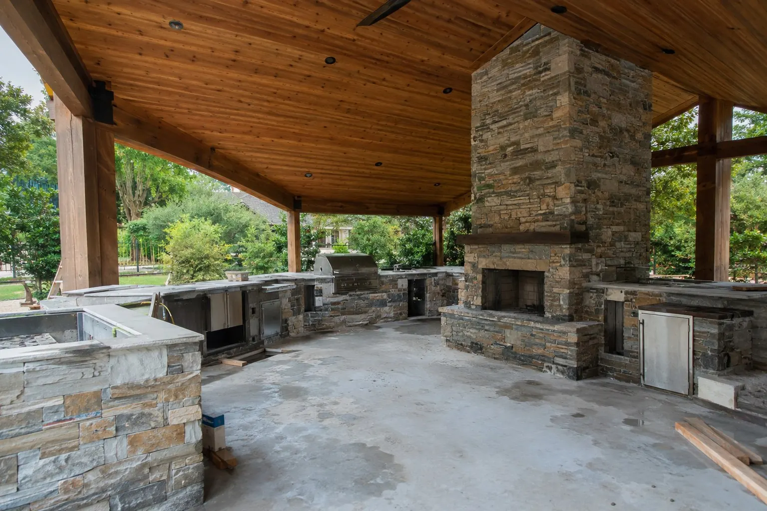 Covered outdoor living space with stone fireplace under construction